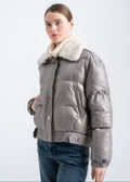 Model wearing a gray lambskin puffer jacket with a soft rex fur collar and snap button closure, featuring a relaxed cropped fit, by Lebeni.