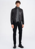 Man wearing a black lamb leather bomber jacket with stand collar, ribbed hem and cuffs, and front zip pockets by Lebeni.