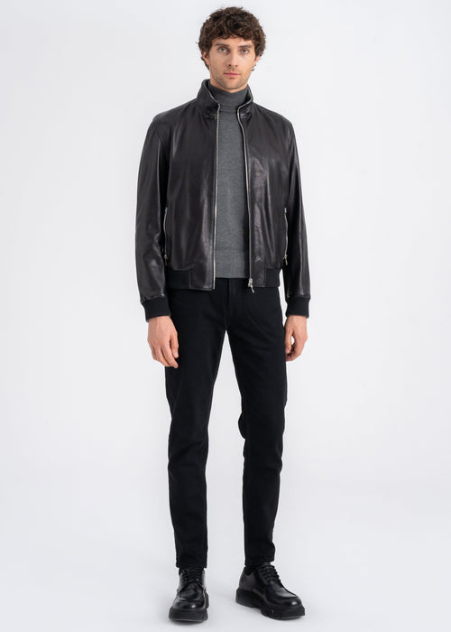Man wearing a black lamb leather bomber jacket with stand collar, ribbed hem and cuffs, and front zip pockets by Lebeni.