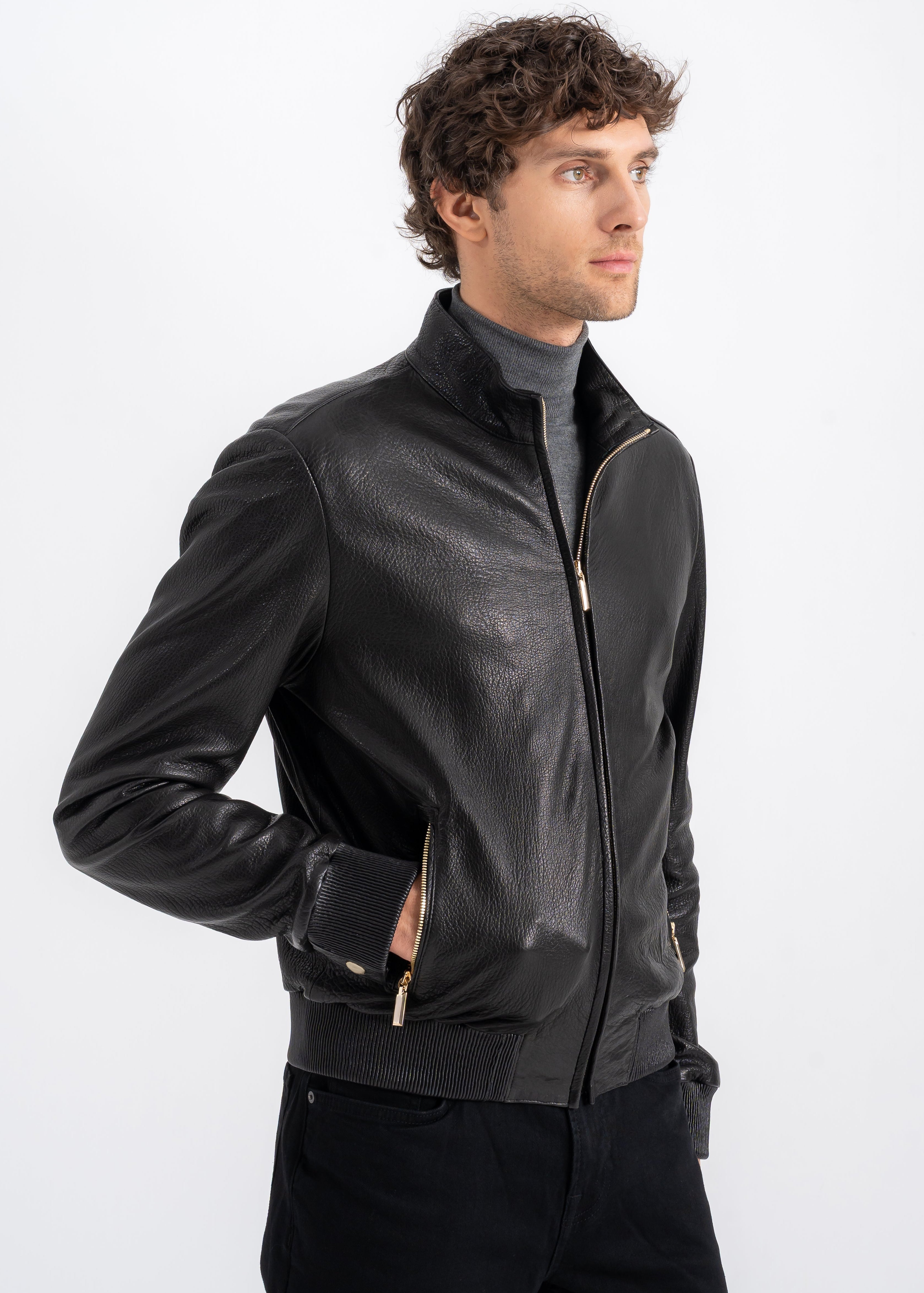 Man wearing a black lambskin bomber jacket with stand collar, rib knit cuffs and hem, and front zip pockets by Lebeni.