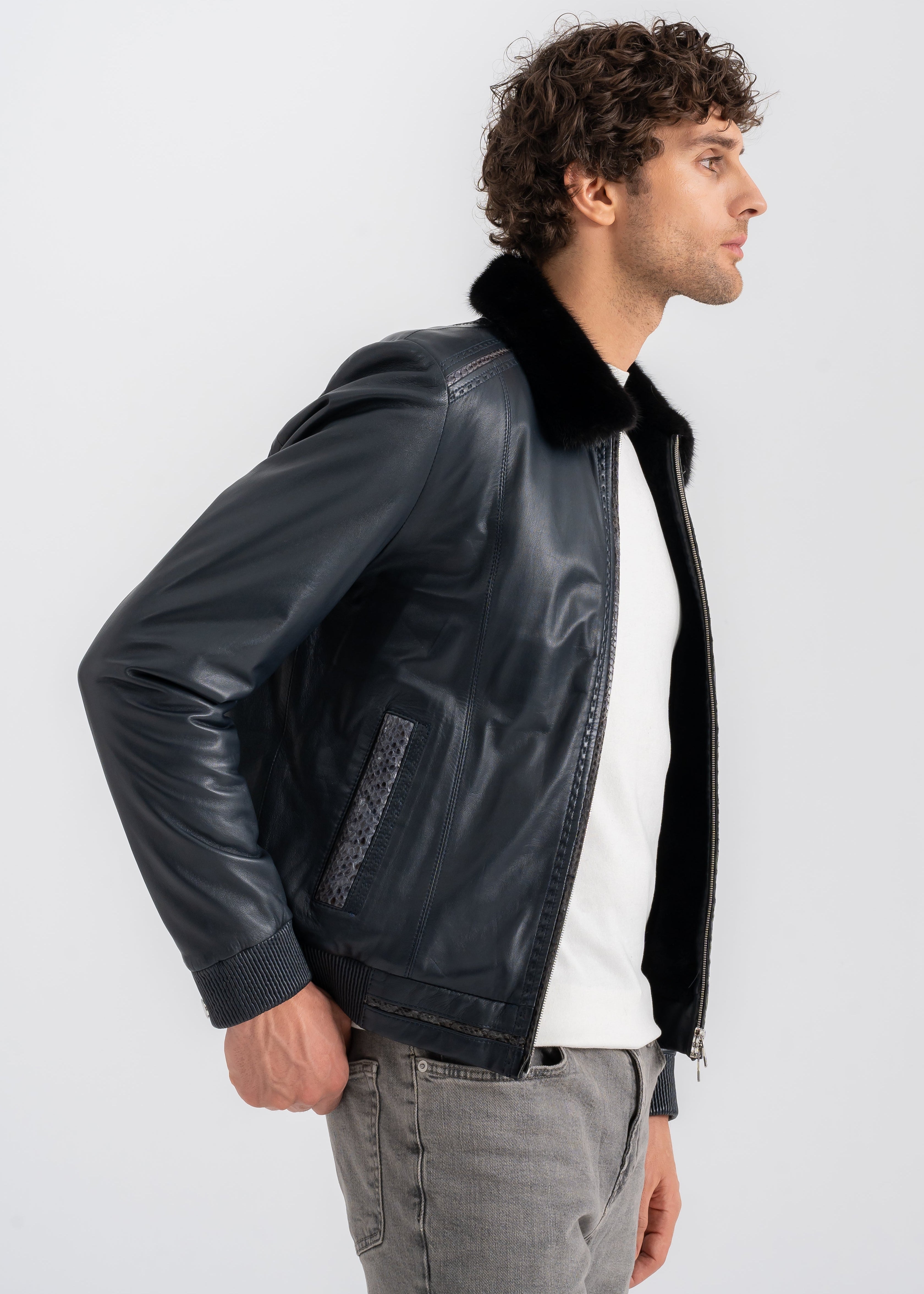 Man wearing a dark navy lambskin jacket with black mink fur collar, python embossed trim on zipper and pockets, and rib knit hem and cuffs by Lebeni.