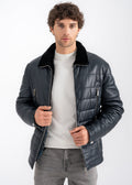 Male model wearing a navy lambskin quilted jacket with black shearling collar, full zip closure, and layered front zip pockets by Lebeni.