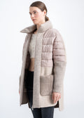 Woman wearing a beige alpaca coat with quilted upper panel, tall rib knit funnel neck, rib knit cuffs and large taupe mink fur patch pockets by Lebeni.