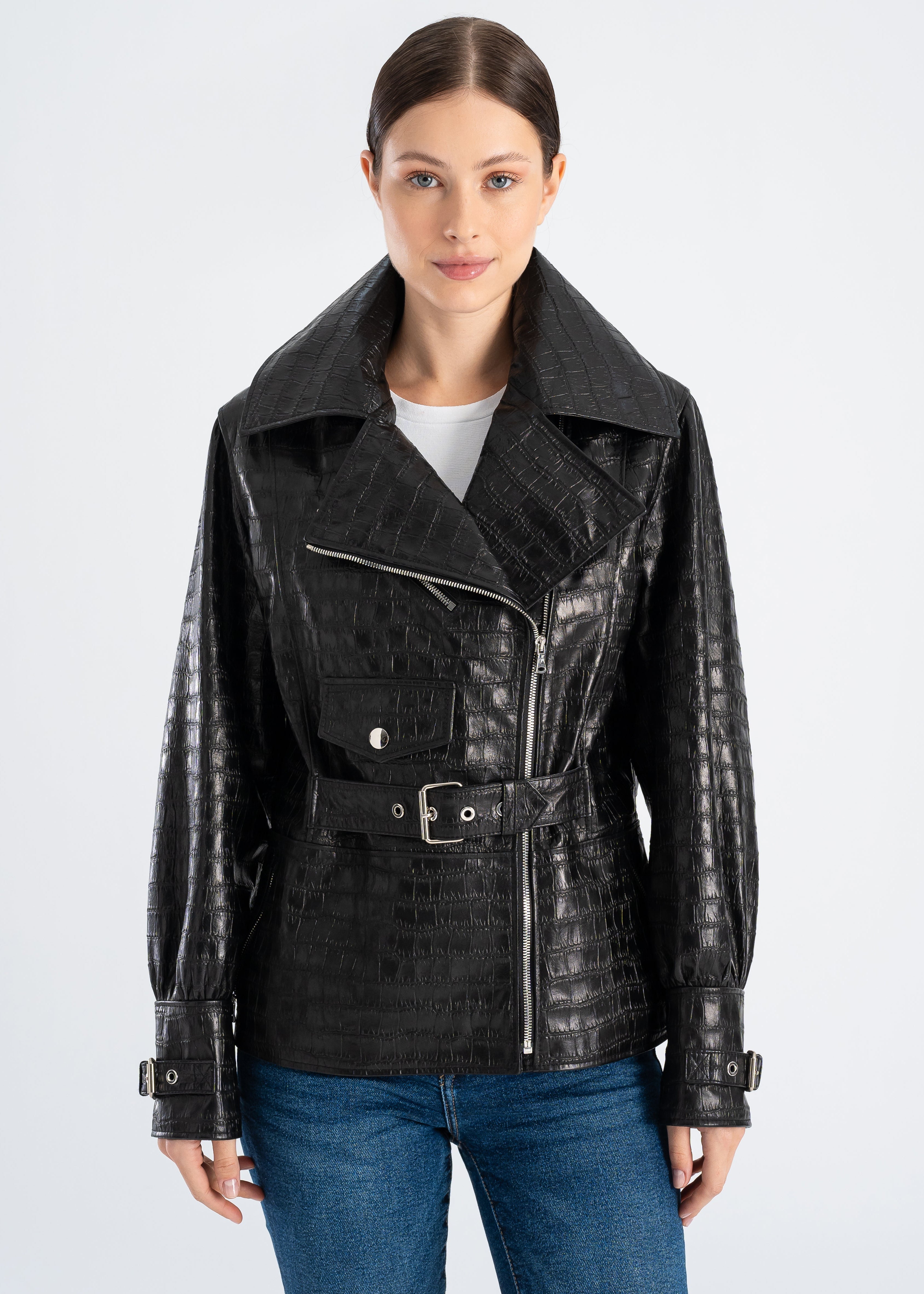 Woman wearing a black croco embossed lambskin leather jacket with wide collar, asymmetric zipper, waist belt, cuff straps and moto style pockets by Lebeni.