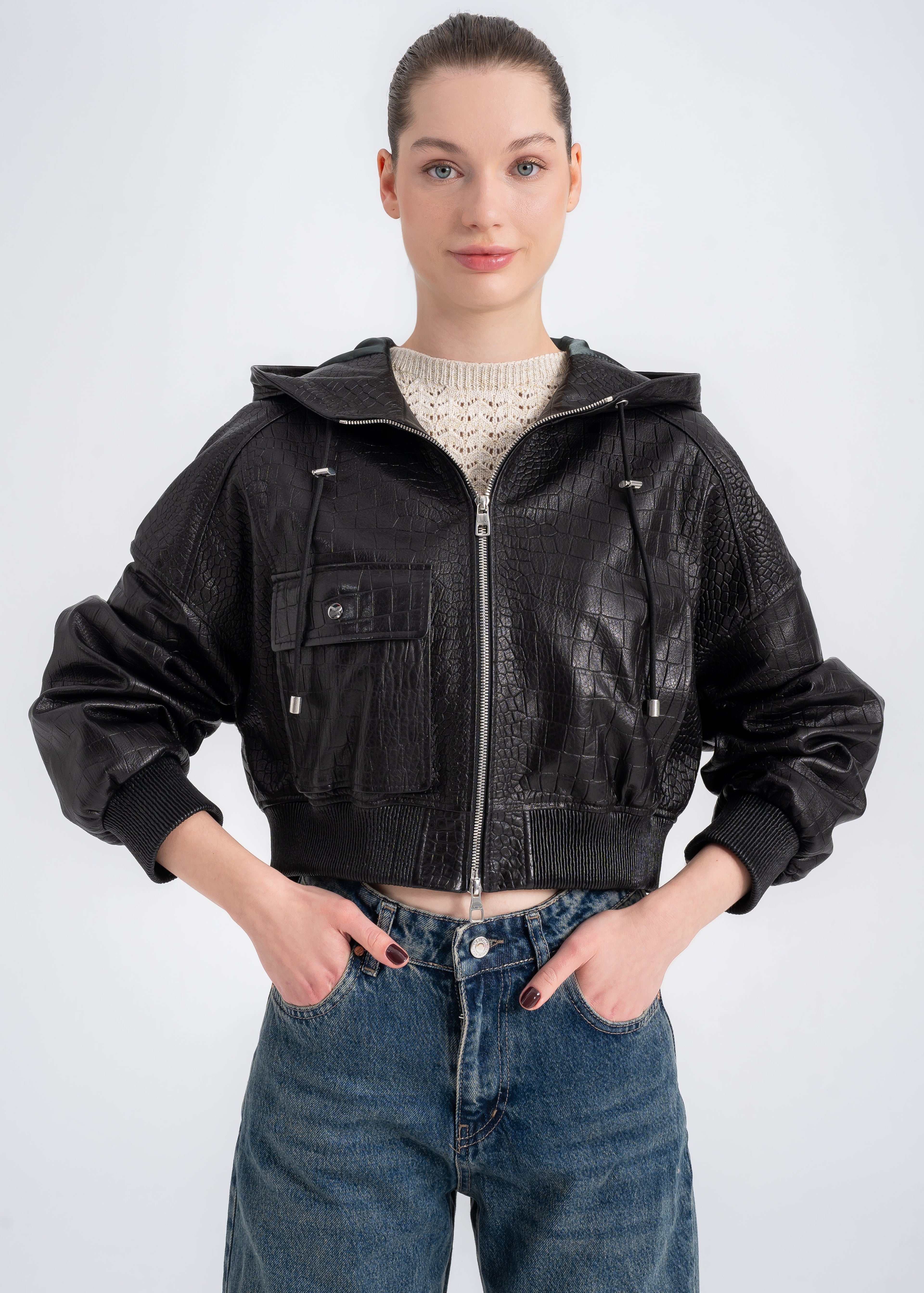 Woman wearing a cropped black crocodile embossed lamb leather hooded jacket with ribbed cuffs and waistband and a front utility pocket by Lebeni.