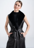 Woman wearing a long black lamb leather sleeveless vest with mink fur shawl collar and waist belt by Lebeni.