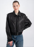Woman wearing a cropped black lambskin bomber jacket with epaulettes, front pockets and ribbed hem by Lebeni.