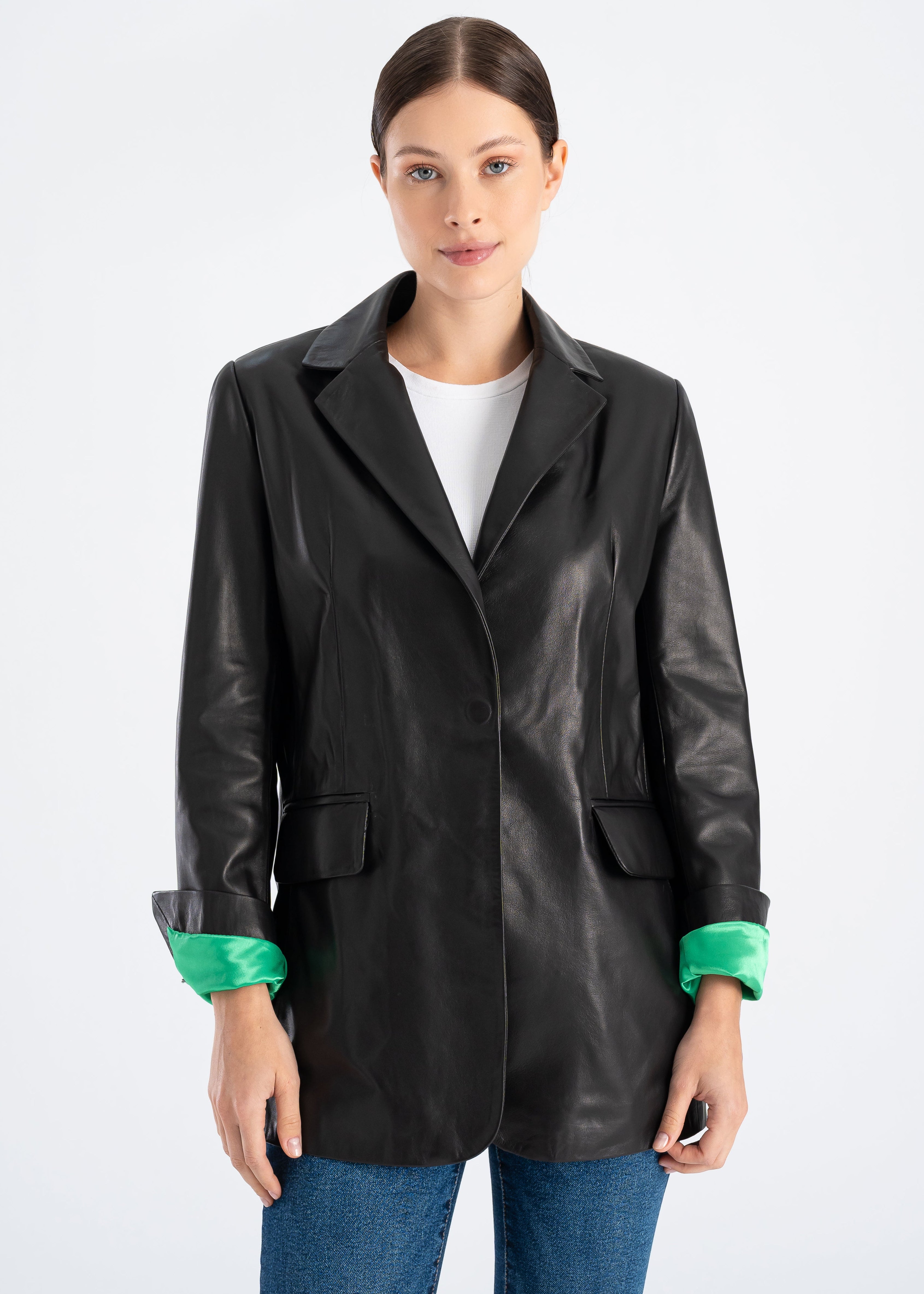 Woman wearing a long black lambskin leather blazer with hidden magnetic front button, tailored hip length fit and bright green satin lining visible at the cuffs by Lebeni.