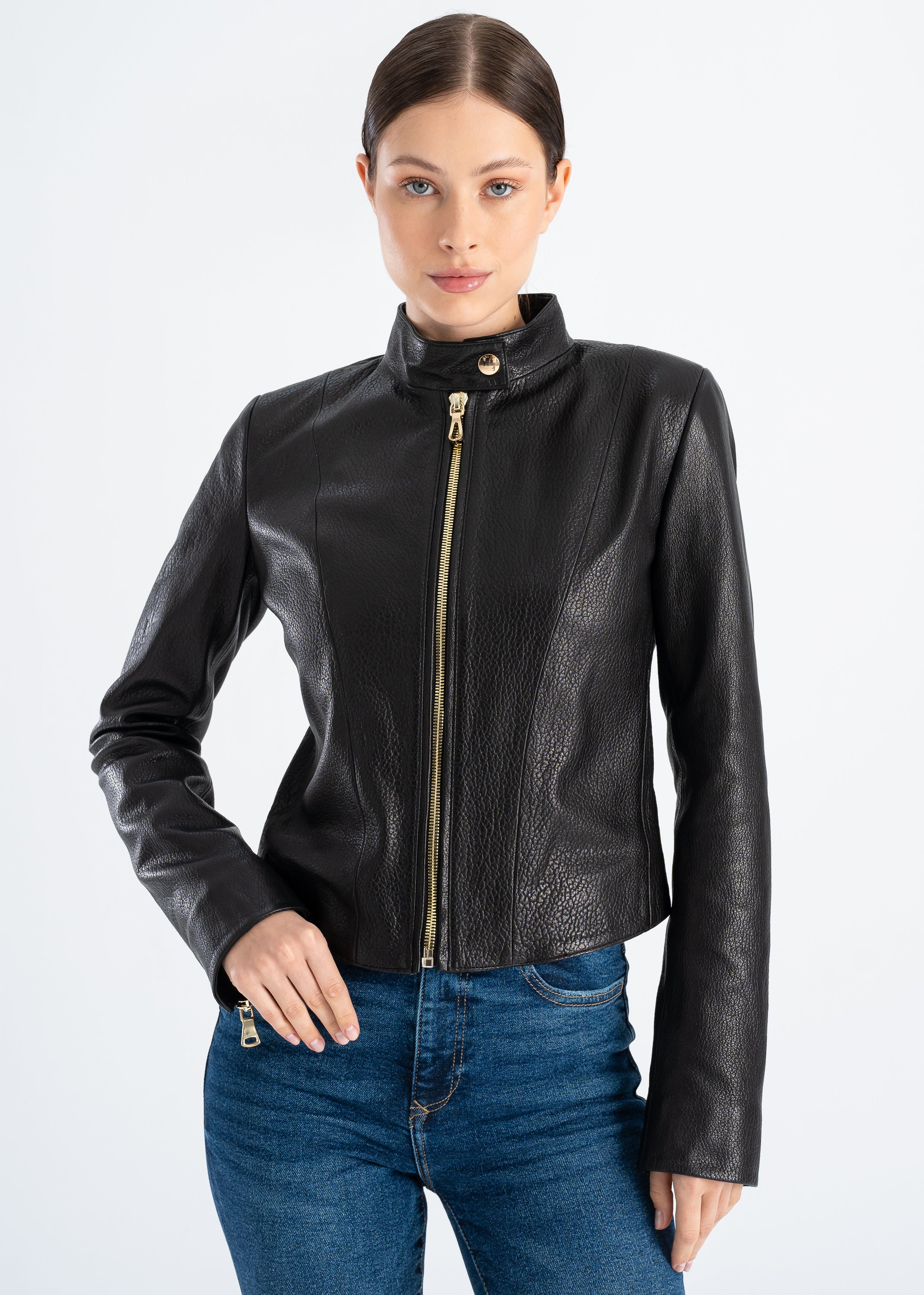 Woman wearing a black lambskin leather jacket with slim tailored fit, stand collar, gold tone front zipper and clean minimalist front, styled with blue denim jeans by Lebeni.