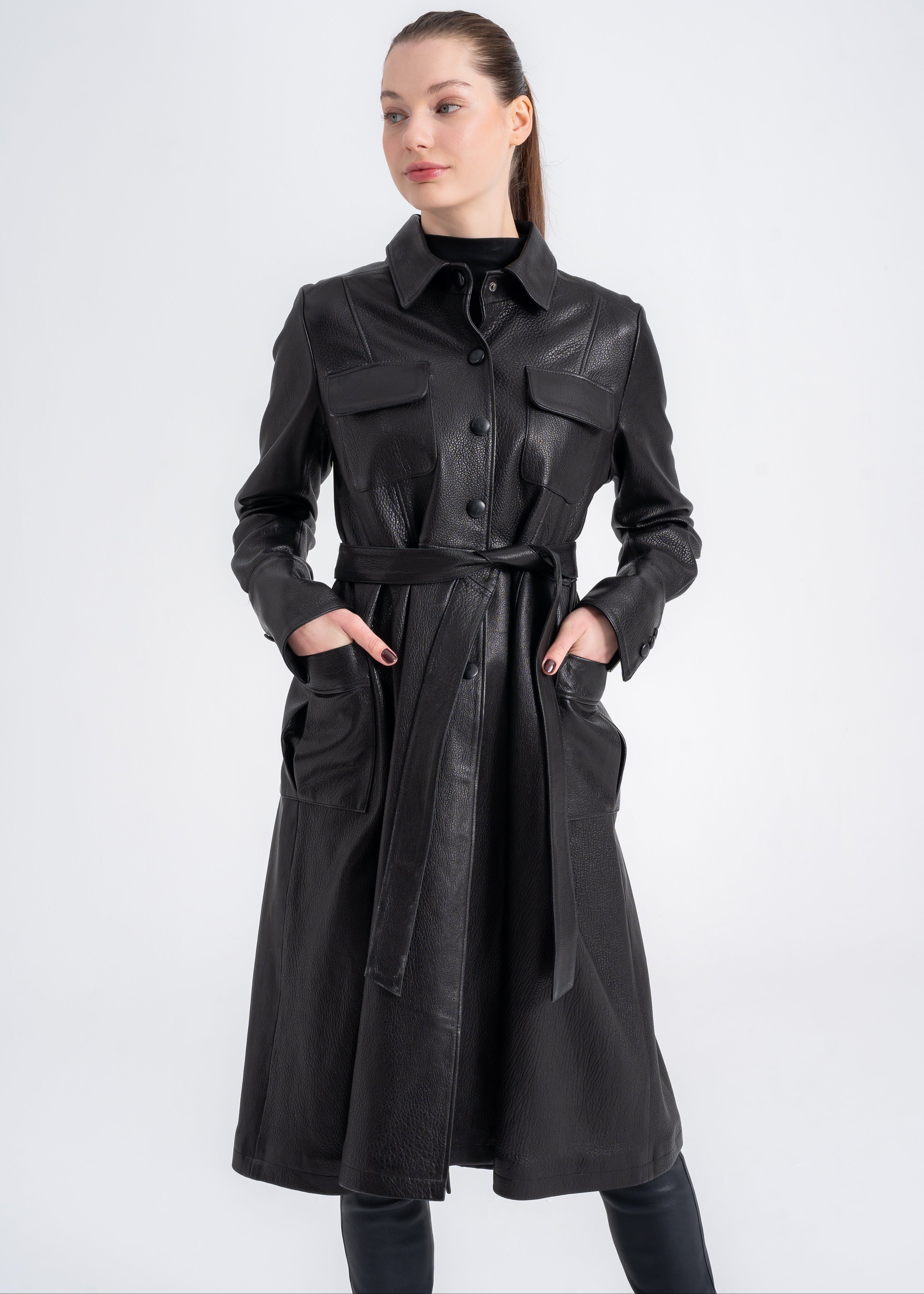 Model wearing a black lambskin utility trench coat with button front, belted waist, and four front pockets by Lebeni.