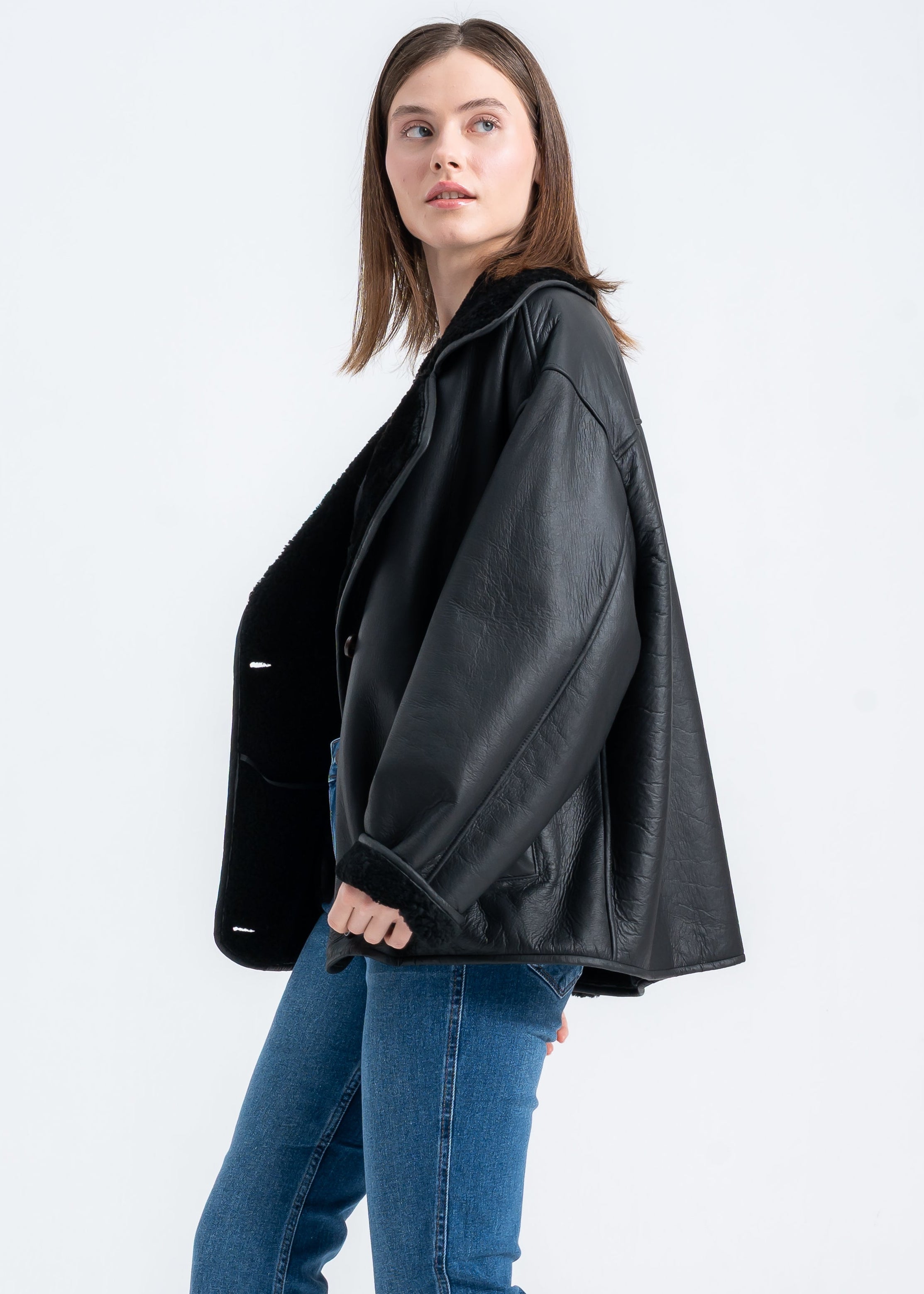 Woman wearing an oversized black shearling deri jacket with wide lapels and relaxed fit by Lebeni.