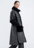 Woman wearing a long black wool and alpaca coat with quilted upper body, high ribbed knit collar and deep front pockets trimmed in black mink fur over checked panels by Lebeni.