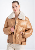 Woman wearing a camel lambskin puffer jacket with soft white real fur collar and boxy cropped silhouette by Lebeni.