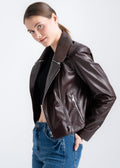 Model wearing a deep mahogany lambskin biker jacket with asymmetrical zipper, wide lapels, and silver hardware by Lebeni.