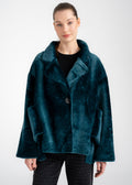 Model wearing a deep teal shearling coat with wide collar, single button closure, and oversized front patch pockets by Lebeni.