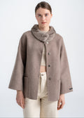 Woman wearing a taupe alpaca wool jacket with rounded mink fur collar, wide sleeves and large front patch pockets by Lebeni.