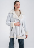 Woman wearing an oversized white shearling biker coat with wide lapels, asymmetric zipper and buckle hem detail by Lebeni.