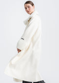 Woman wearing a long winter white wool coat with real light beige mink fur shawl collar, wrap belted design, wide ribbed knit cuffs and knit trimmed front pockets by Lebeni.